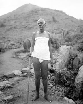 Bhagavan Ramana standing near Arunachala with his walking stick